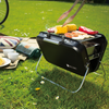 Valiant Nomad portable BBQ, lit with hot charcoal and cooking an assortment of BBQ food.